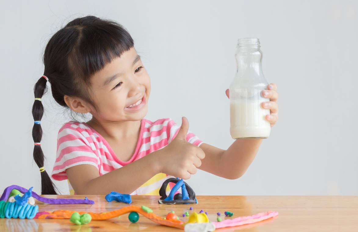 Seorang anak sedang minum susu yang kaya zat besi